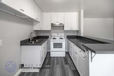A kitchen with white cabinets and black countertops.