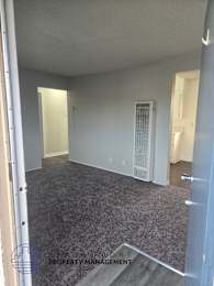 A room with a carpeted floor and a door on the right side.