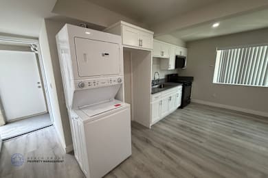A white dishwasher is in a kitchen with wood flooring.