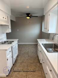 A kitchen with white cabinets and a tile floor.