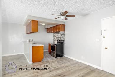 A kitchen area with a white ceiling fan and wooden cabinets.