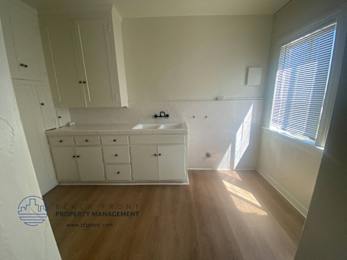 A kitchen with white cabinets and a wooden floor.