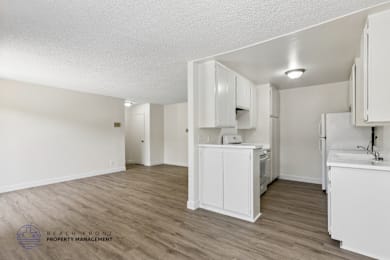 A kitchen with white cabinets and a wooden floor.