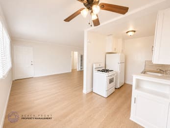 A kitchen with a fan and wooden floors.