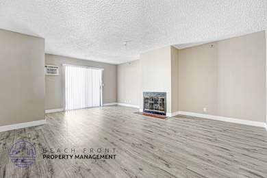 A spacious room with a fireplace and a logo for Beach Front Property Management.