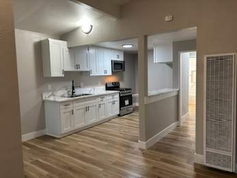A kitchen with white cabinets and a wooden floor.