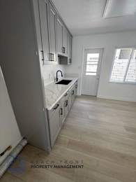 A kitchen with wooden floors and white walls.
