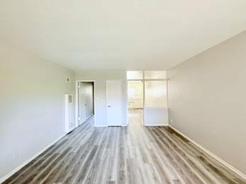 A long, empty hallway with white doors and wood flooring.