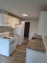 Floor Plan  A kitchen with a granite countertop and white appliances.