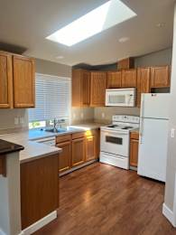 A modern kitchen with wooden cabinets and a skylight.