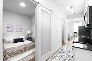 Floor Plan  A bedroom with a bed, a television, and a kitchen area.