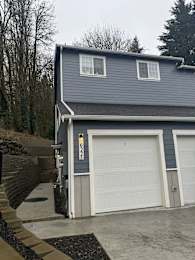 A two-car garage with a grey house in the background.