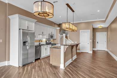 A modern kitchen with wooden floors and stainless steel appliances at The Knights @ 506 Delaware Apartments, Buffalo, NY