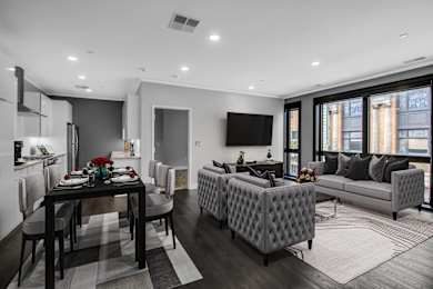 a living room with grey and white furniture and a table with chairs at Nineteen North Apartments , Buffalo, NY
