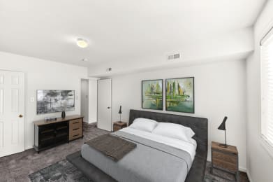 a white bedroom with a bed and two paintings on the wall