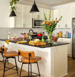 A kitchen with a black counter top and white cabinets.