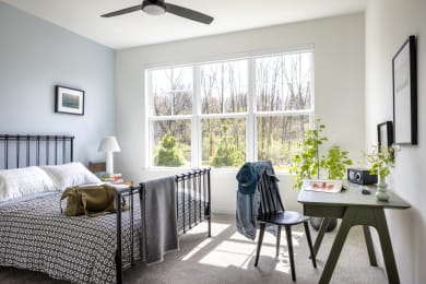 a bedroom with a bed and a large window and a desk with a chair