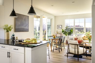 a kitchen with a counter top and a dining room with a table and chairs