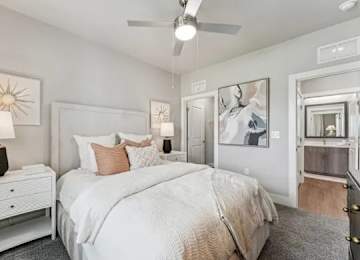 A bedroom with a large bed, a ceiling fan, and a dresser.