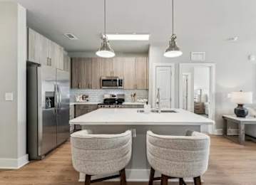 A modern kitchen with a white island and two chairs.