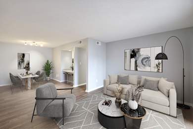 A modern living room with a grey sofa, a round coffee table, and a dining table with chairs.