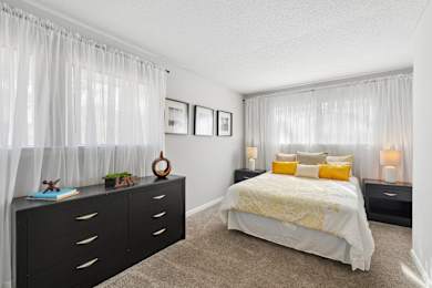 A bedroom with a bed, nightstands, and pictures on the wall.