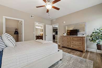 A bedroom with a large bed, a dresser, and a ceiling fan.