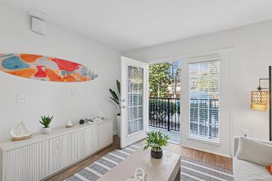 A living room with a white couch, a coffee table, and a surfboard artwork on the wall.