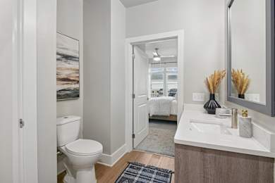 A bathroom with a toilet, sink, and mirror.