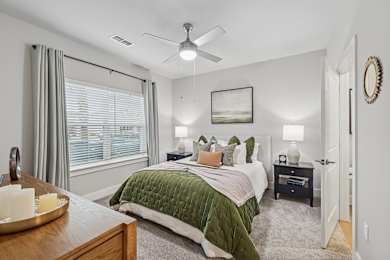 A bedroom with a bed, nightstand, and window.