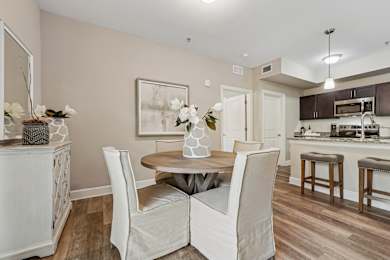 A dining room with a table set for two and a kitchen in the background.