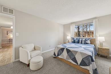 A bedroom with a bed, chair, and window.