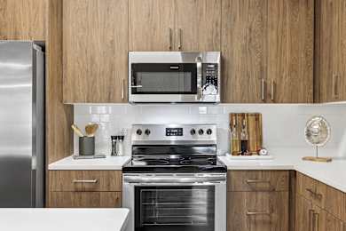 A modern kitchen with a stainless steel refrigerator, a microwave, and a stove top oven.