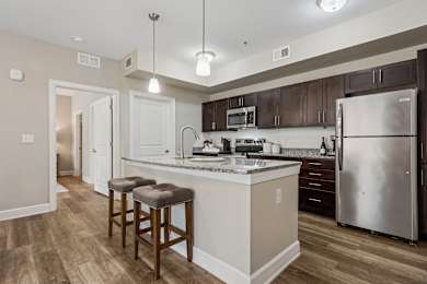 A kitchen with a white counter top and a stainless steel refrigerator.