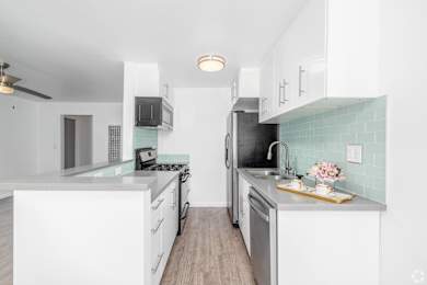 A kitchen with white cabinets and a green backsplash.