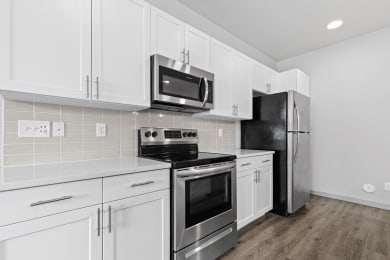 Floor Plan  a kitchen with white cabinets and stainless steel appliances