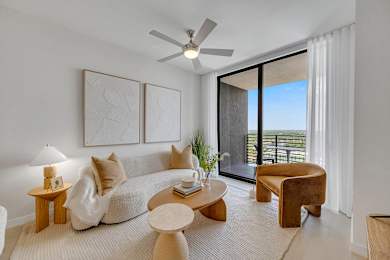 A living room with a white couch, a wooden coffee table, and a ceiling fan.
