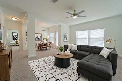 A living room with a black couch, a coffee table, and a ceiling fan.