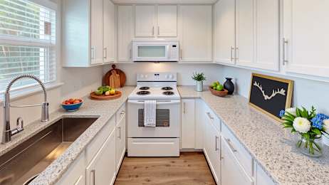 A kitchen with white cabinets and a stove top oven.