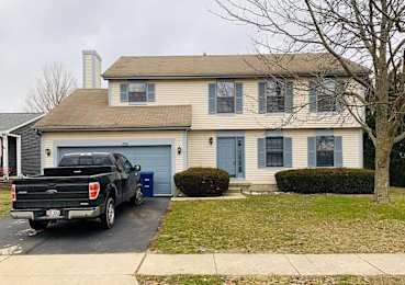 A black Ford truck is parked in front of a two-story house with a blue garage door.