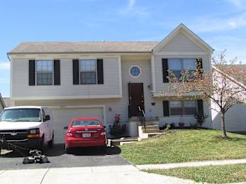 A two-story house with a red car parked in front.