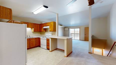 A kitchen with a white refrigerator and wooden cabinets.