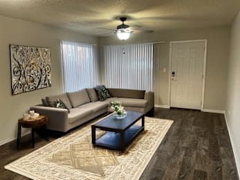 A living room with a grey couch, a coffee table, and a ceiling fan.