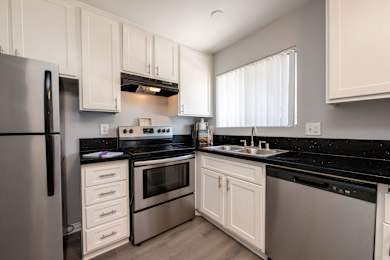 A modern kitchen with white cabinets and black countertops.