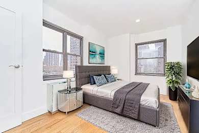 A bedroom with a bed, nightstand, and a painting on the wall.