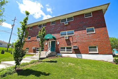 A red brick building with a green awning and a white door.