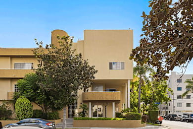 A beige building with a tree in front of it.