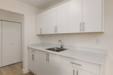 A kitchen with white cabinets and a sink.