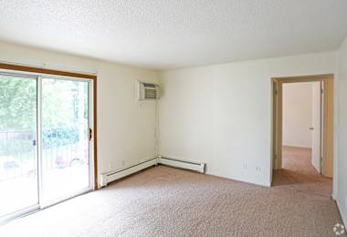 an empty living room with white walls and a sliding glass door