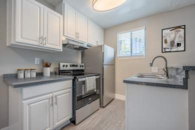 A kitchen with white cabinets and a black stove top oven.